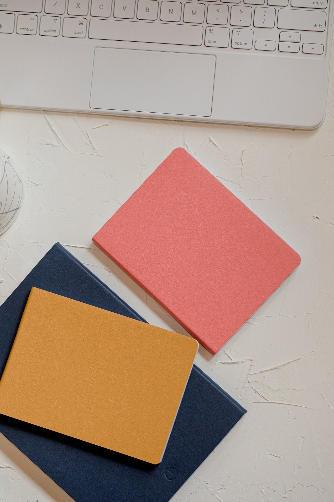 Flatlay of notebooks beside a laptop keyboard