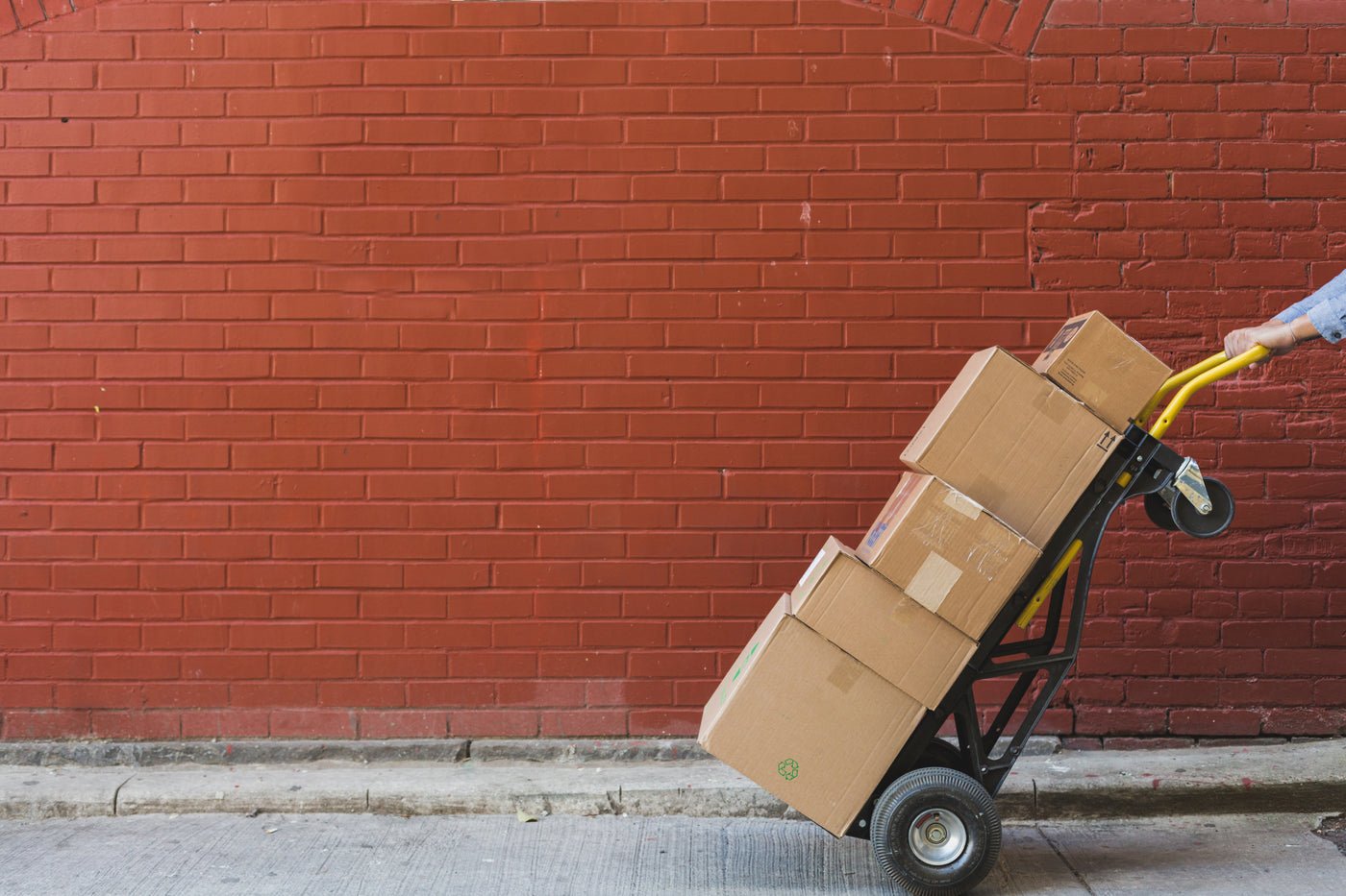 Stacked shipping boxes against a red brick wall